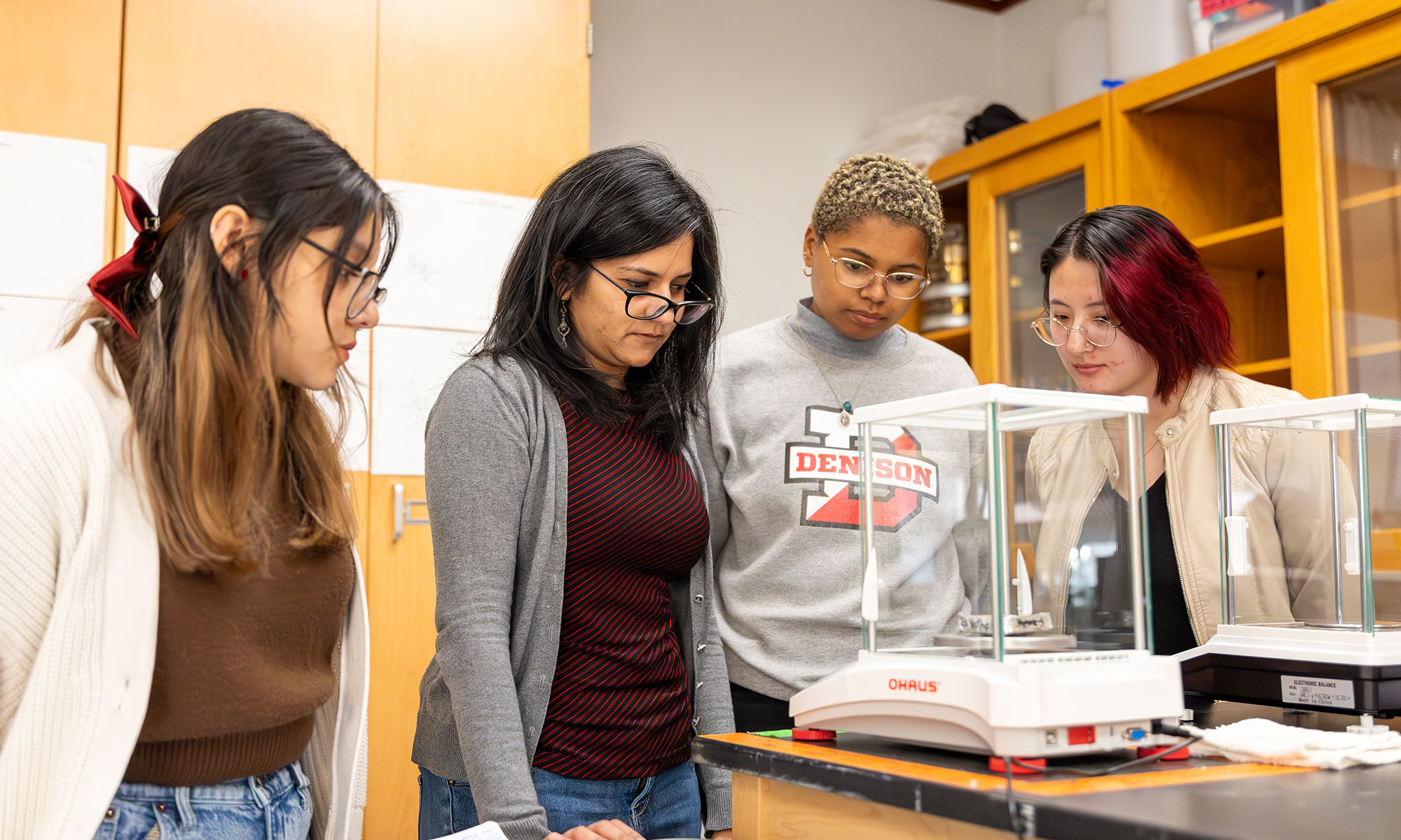 Students and faculty member looking at something in a lab
